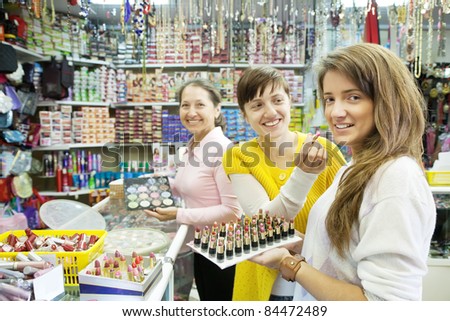 Three women chooses   lipstick at cosmetics  shop