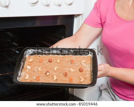 Closeup of female hands puts dough  into oven. One of the stages of cooking of  honey cake.  See series