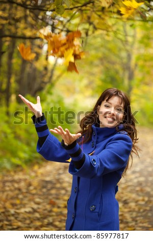 Girl in blue coat throw up yellow leaves