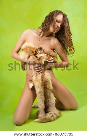 Nudity woman covered with a fox fur on green background