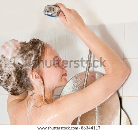 Long-haired girl shampooes with foam in bath