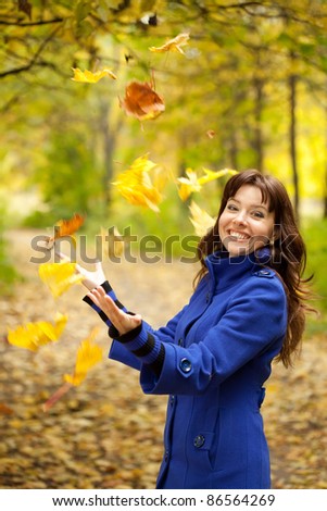 Girl in blue coat throw up maple leaves