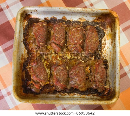 baked stuffed beef in roasting pan on checked tablecloth. One of the stages of preparation of  stuffed beef.  See series