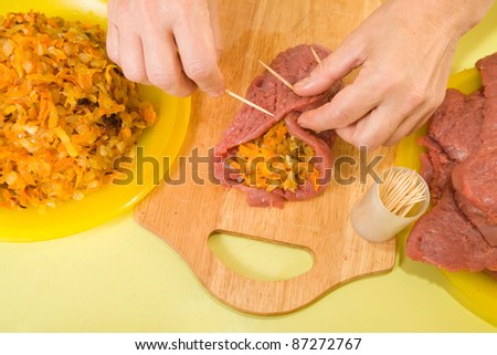 Closeup of cook sewing stuffed beef by toothpicks. One of the stages of preparation of the stuffed beef.  See series
