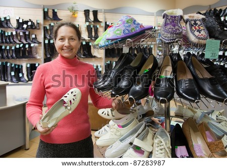 Mature woman chooses shoes at shoes shop