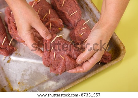 Closeup of cook hands puts stuffed beef to cook griddle. One of the stages of preparation of the stuffed beef.  See series