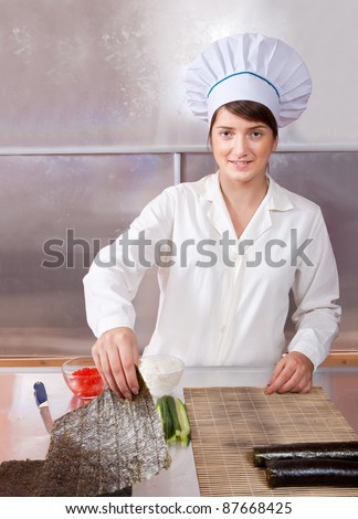 Cook woman making  japanese sushi rolls in kitchen