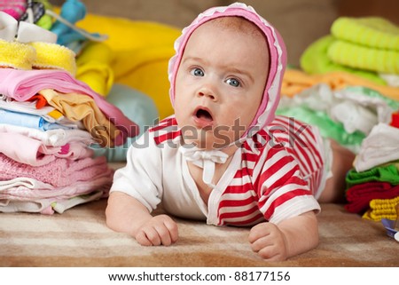 baby girl with stacked of children\'s clothes