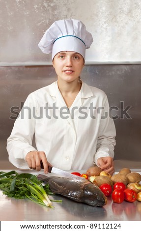 Cook woman with carp fish in kitchen