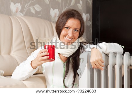 smiling woman   near warm radiator  in home