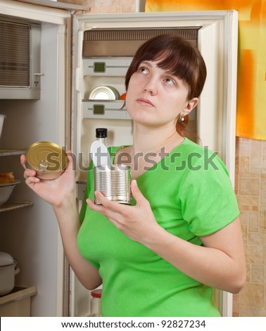 Young woman putting with metal can near fridge at home