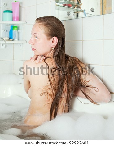 Rear view of long-haired girl sitting in bath