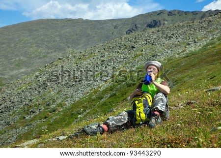 Female tourist drinking water from bottle at mountain