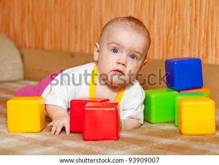 Baby girl plays with toy blocks in home