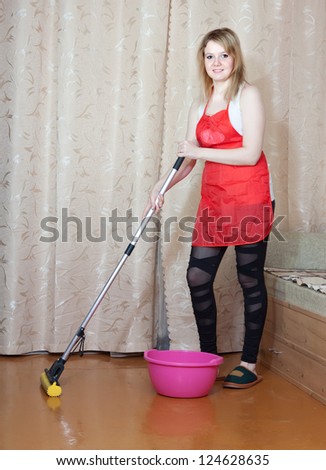 woman washes the floor with mop in the living room