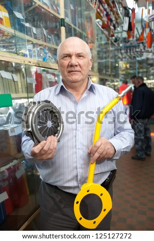 mature man holds  engine clutch  in  auto parts store