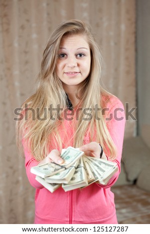 happy casual girl with bundles of US dollars  in home interior