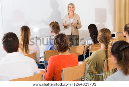 Mature female speaker giving presentation for students in lecture hall