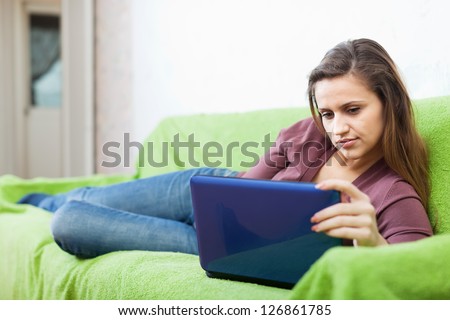 woman with netbook lying down on sofa in living room