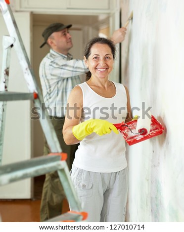 Smiling woman and man makes repairs in home interior