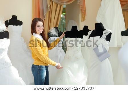 Smiling pretty bride chooses wedding outfit in bridal boutique