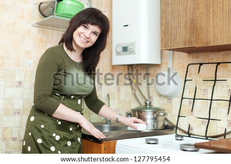 woman cleans the kitchen sink with melamine sponge