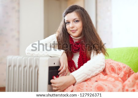 Smiling long-haired woman near oil heater