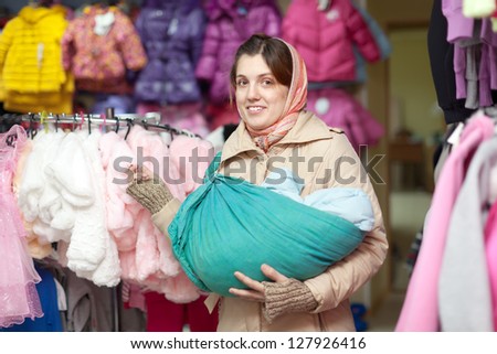 woman with baby in sling  at clothes shop