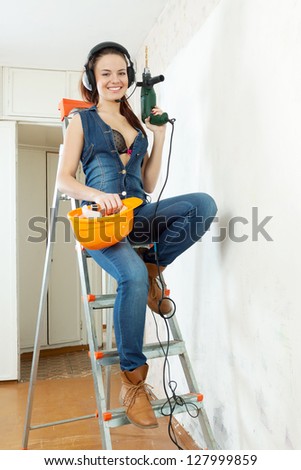 Sexy beautiful girl in headphones with tools on staircase