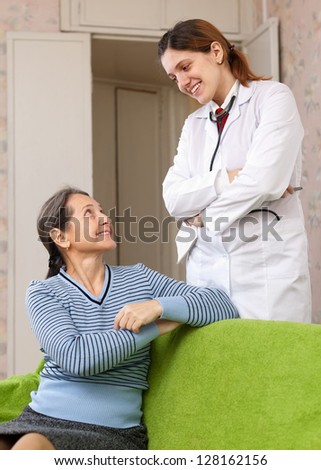 friendly doctor talks with happy mature woman at hospital
