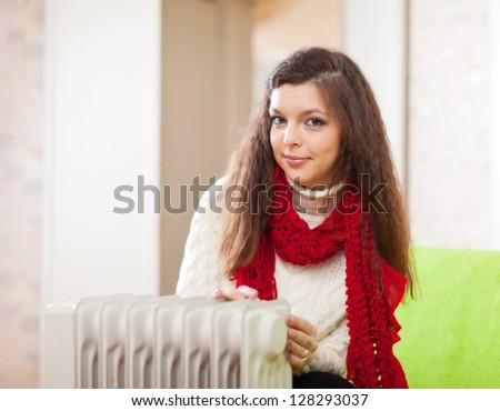 Long-haired woman near oil heater in home