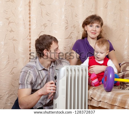 Family  relaxing at home near oil heater