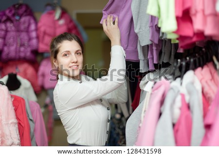 Smiling woman chooses clothes at clothing store