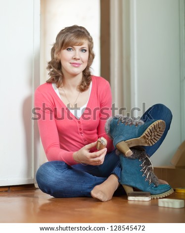 Woman sits on floor and cleans footwear