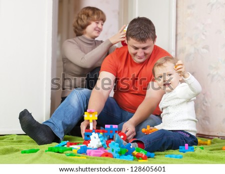 Happy parents and child plays with meccano set in home