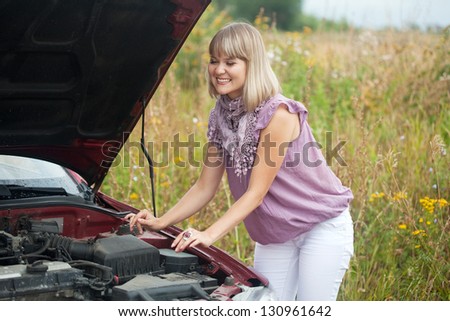 young woman with her broken car in summer day