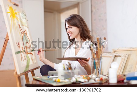 Happy Young Woman Paints Landscape On Canvas In Workshop