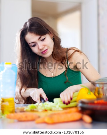 beautiful woman cutting green celery at her kitchen at home