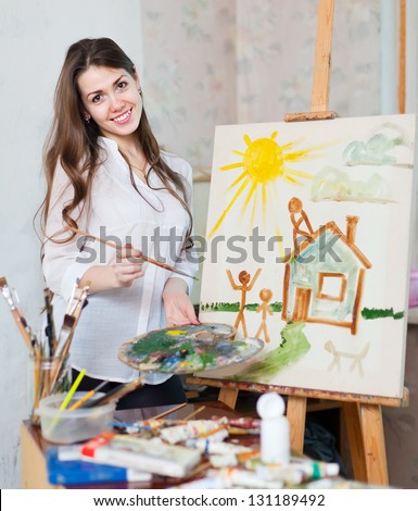 Happy young woman paints home  in workshop