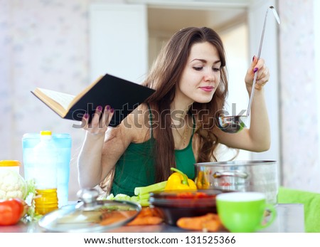 Beautiful Housewife Cooking With Ladle And Cookbook In Kitchen
