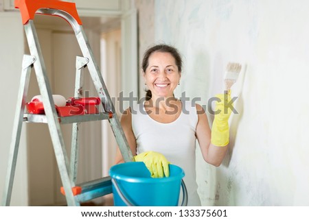 Mature woman makes repairs in the apartment