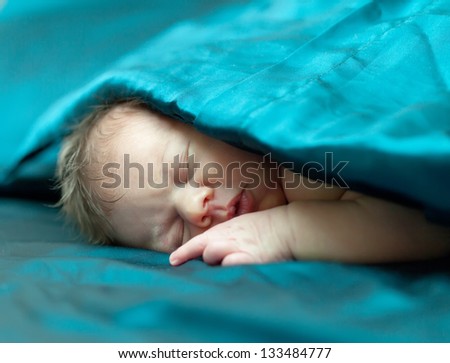 newborn baby sleeps under blanket