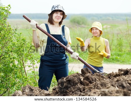 Two women works with animal manure at field - stock photo