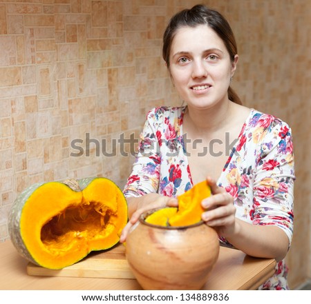 young woman cooking pumpkin in pot at  kitchen