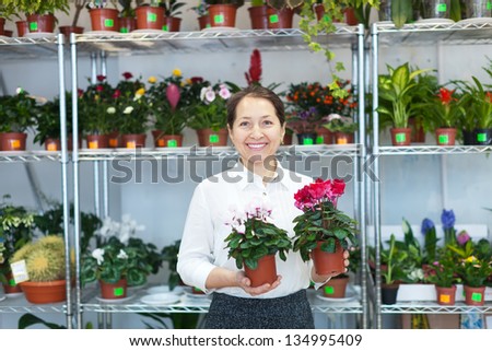 Happy mature woman with Cyclamen plant in flower store