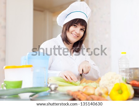 Portrait of female cook with celery on cutting board at kitchen