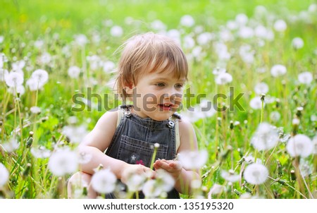 Two-year child at dandelion meadow in summer