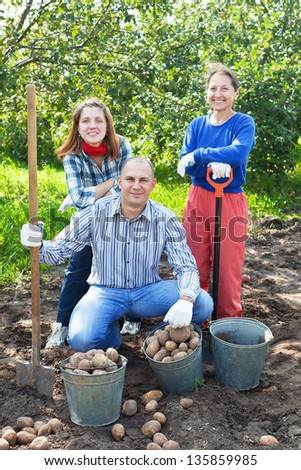 Happy family harvesting potatoes in vegetable garden