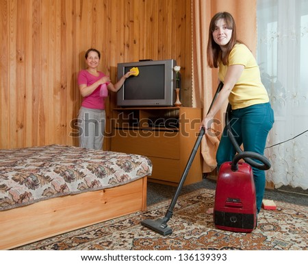 Women cleaning with vacuum cleaner in living room