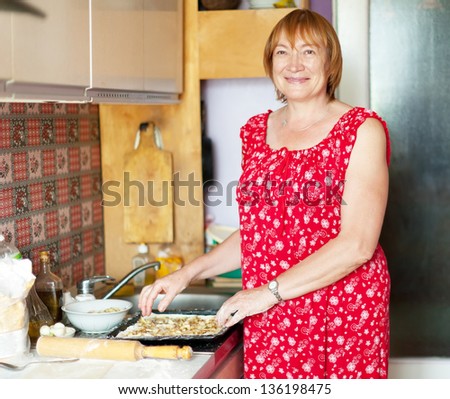 Mature woman makes pasty with fillings in her kitchen
